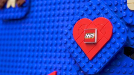 LEGO's logo is shown on LEGO bricks in a red heart on a blue background.