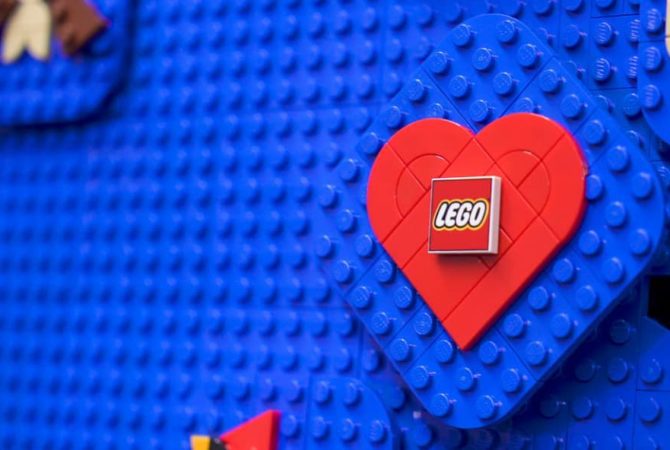 LEGO's logo is shown on LEGO bricks in a red heart on a blue background.