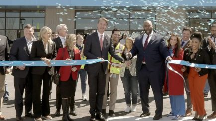 Governor Glenn Youngkin and local leaders cut a ceremonial ribbon at an Amazon facility opening, surrounded by partners and employees under celebratory confetti.