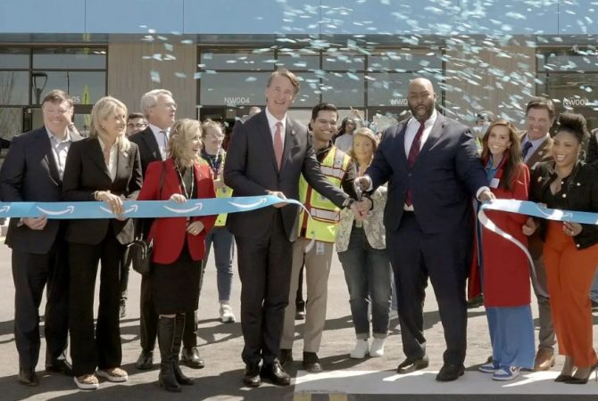Governor Glenn Youngkin and local leaders cut a ceremonial ribbon at an Amazon facility opening, surrounded by partners and employees under celebratory confetti.