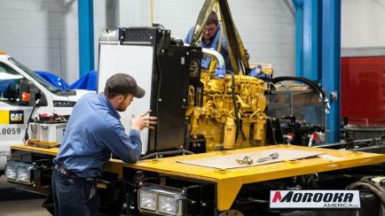 Two workers assemble heavy machinery at Morooka America’s U.S. manufacturing facility.