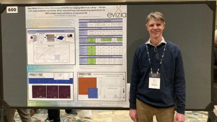 VCU physics professor Jason Reed standing with his presentation board on his creation of a microscopic instrument to further optimize manufacturing of its advance system.