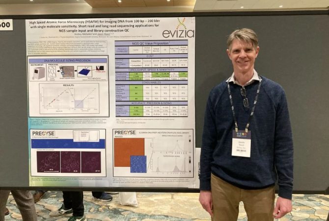 VCU physics professor Jason Reed standing with his presentation board on his creation of a microscopic instrument to further optimize manufacturing of its advance system.