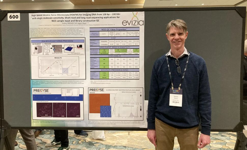 VCU physics professor Jason Reed standing with his presentation board on his creation of a microscopic instrument to further optimize manufacturing of its advance system.